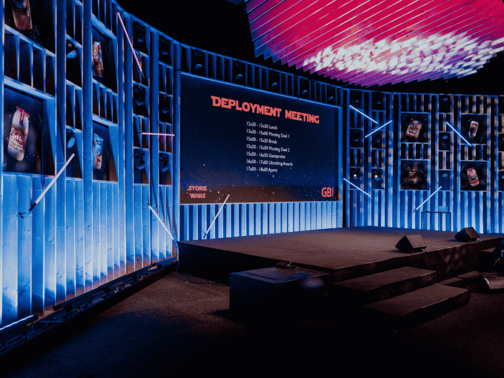 Podiumopstelling met 'Store Wars' thema en blauwe LED-verlichting tijdens een zakelijke Deployment Meeting
