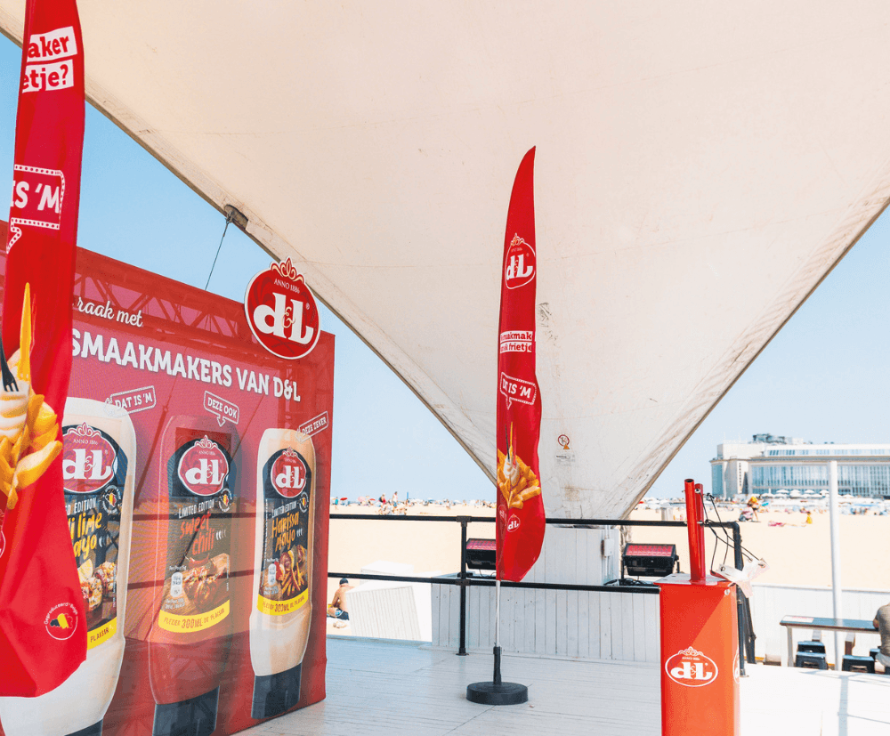 D&L-brand activation op het strand met rode vlaggen en een katapultsysteem met presentatie van verschillende sauzen.
